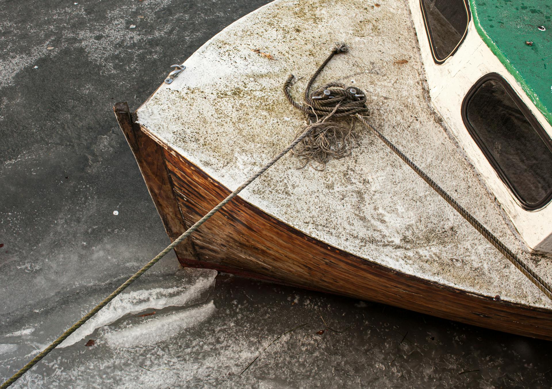 A top-down view of an old wooden boat with a rope tied, located in the icy waters of Copenhagen.