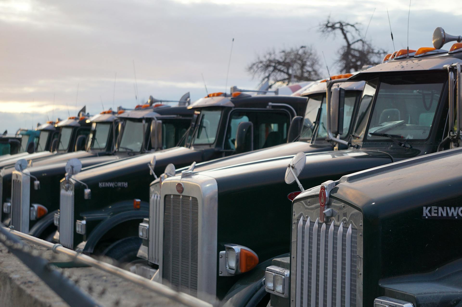 Classic Kenworth trucks lined up outdoors, showcasing heavy-duty retro design.