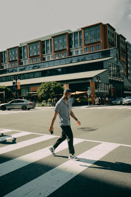 Man in Blue Polo Shirt and Black Pants Walking on a Pedestrian Lane