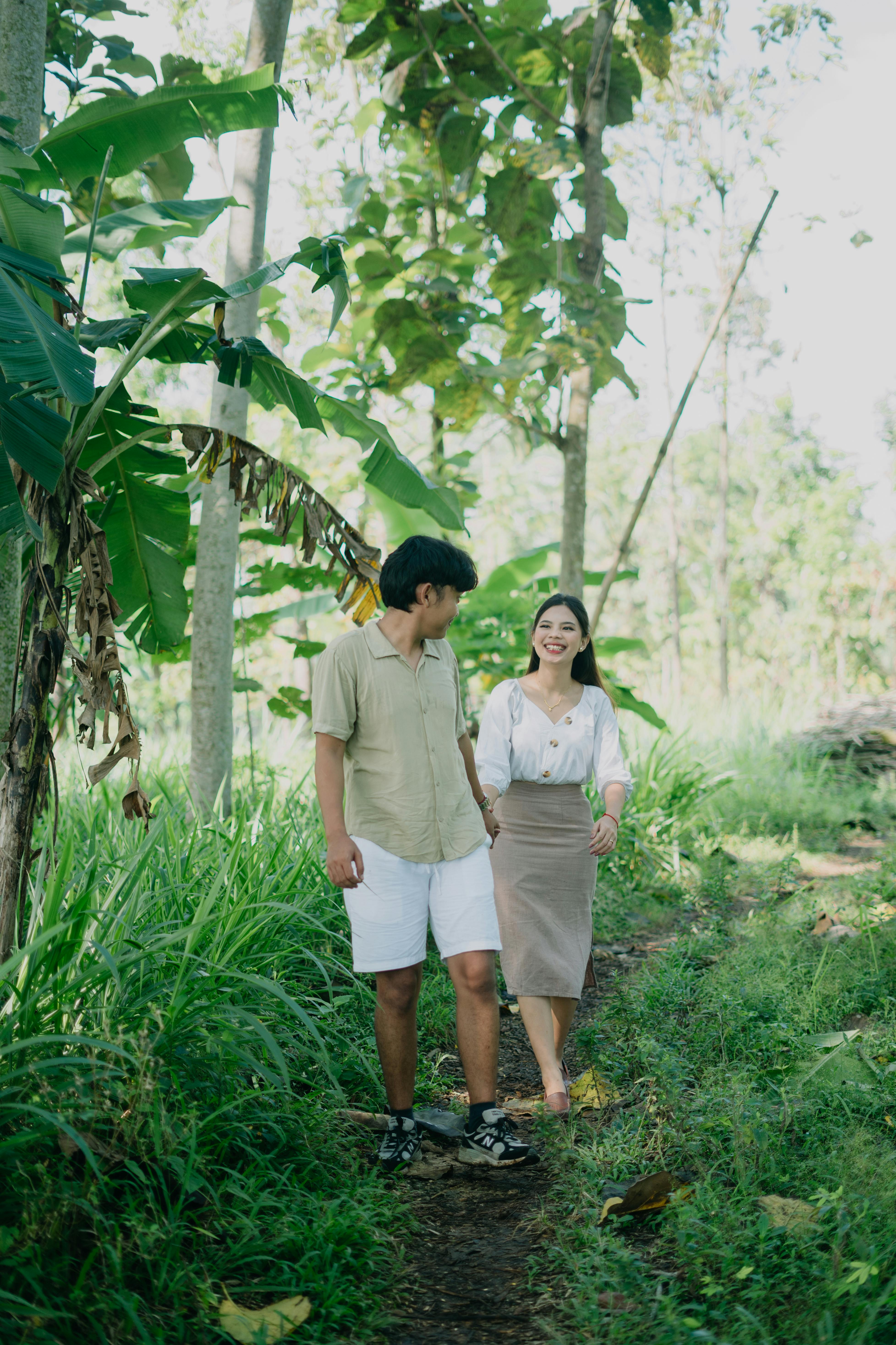 Smiling couple enjoying a walk through a vibrant tropical forest, capturing nature's tranquility.