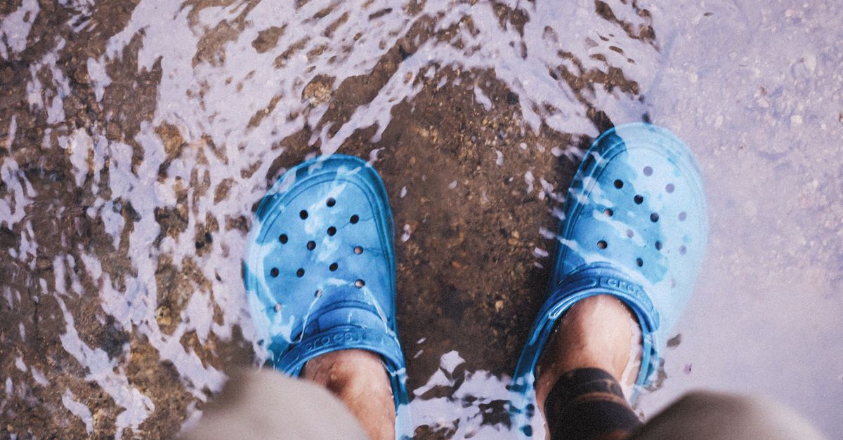Close-up of blue shoes in a shallow stream, showcasing casual waterproof footwear.