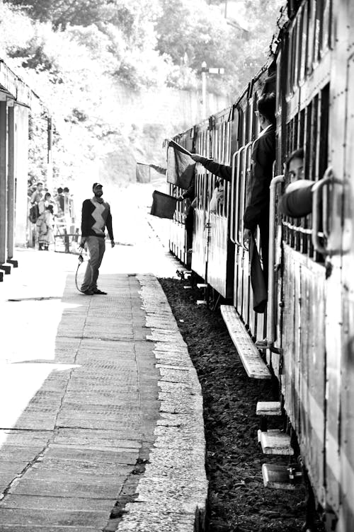Free Monochrome Shot of a Man Standing next to a Train Stock Photo