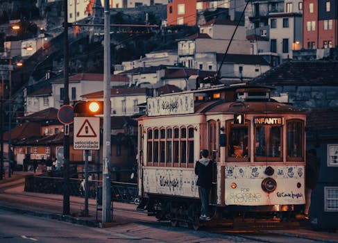 A historic tram on Route 1 travels through Porto, Portugal at sunset.
