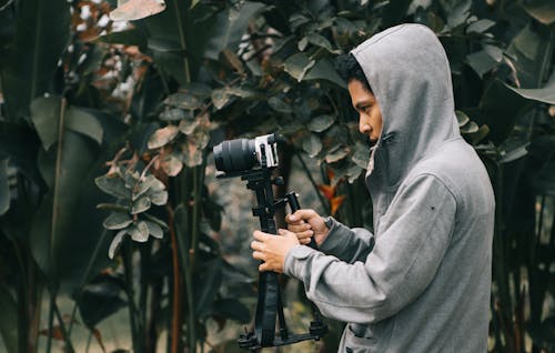 Free Man in Hooded Jacket Holding Camera With Stablizer Stock Photo