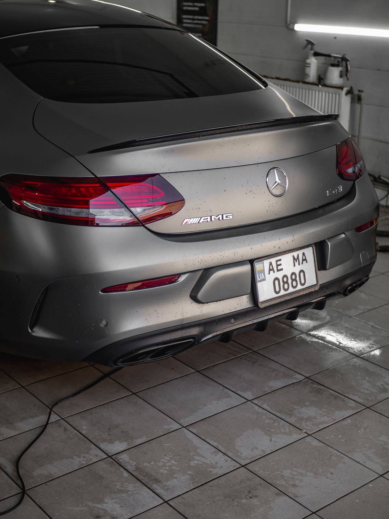 Coupe parked on wet tiles inside a modern wash station