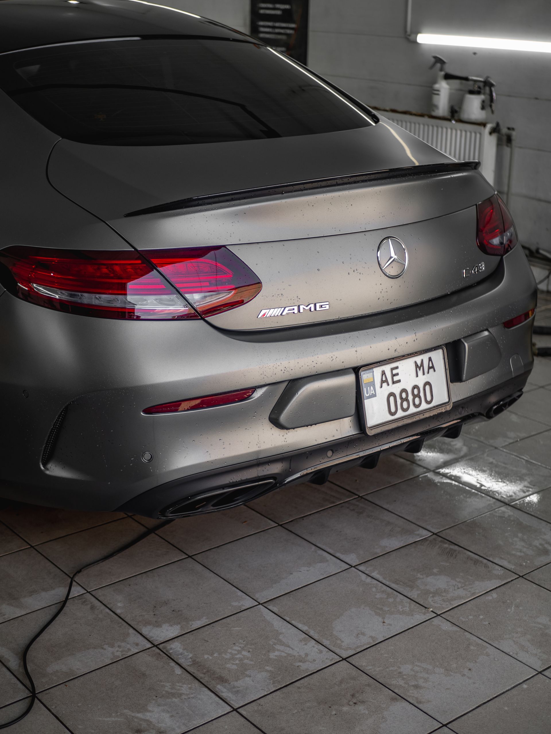 Coupe parked on wet tiles inside a modern wash station