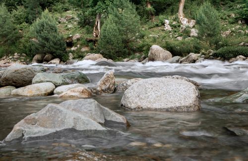Free Peaceful image of a river rushing over rocks in a vibrant forest setting, ideal for nature themes. Stock Photo