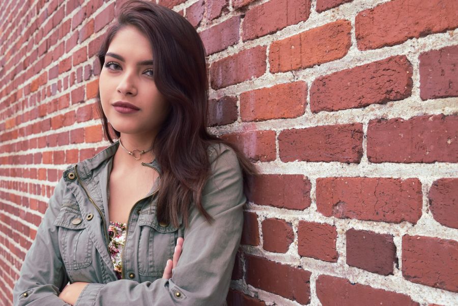 A woman leaning against a brick wall — photo by Jonathan Meza on Pexels