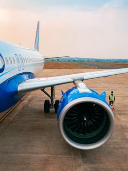 Close-up of a commercial airplane on a runway showcasing its turbine engine under a clear sky.