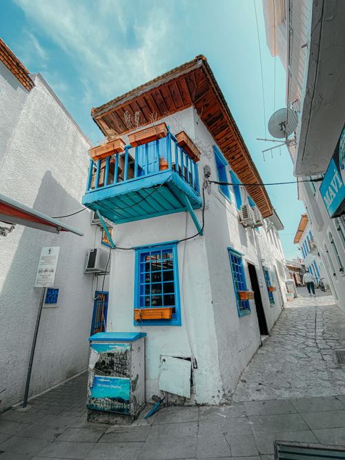 Free White building with blue windows and balcony in a narrow alley of a historic town. Stock Photo
