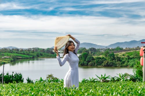 Free Photo of a Woman in a White Dress Holding an Asian Conical Hat Stock Photo
