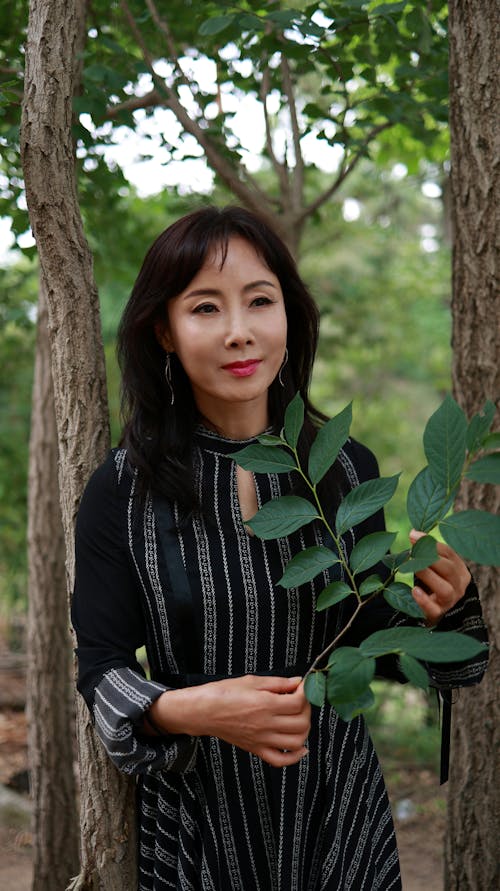 A Woman in Black Dress Holding Leaves