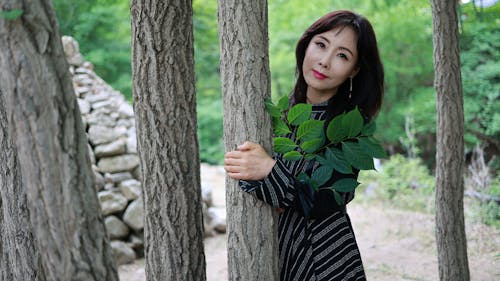 A Woman in Black Dress Holding Leaves