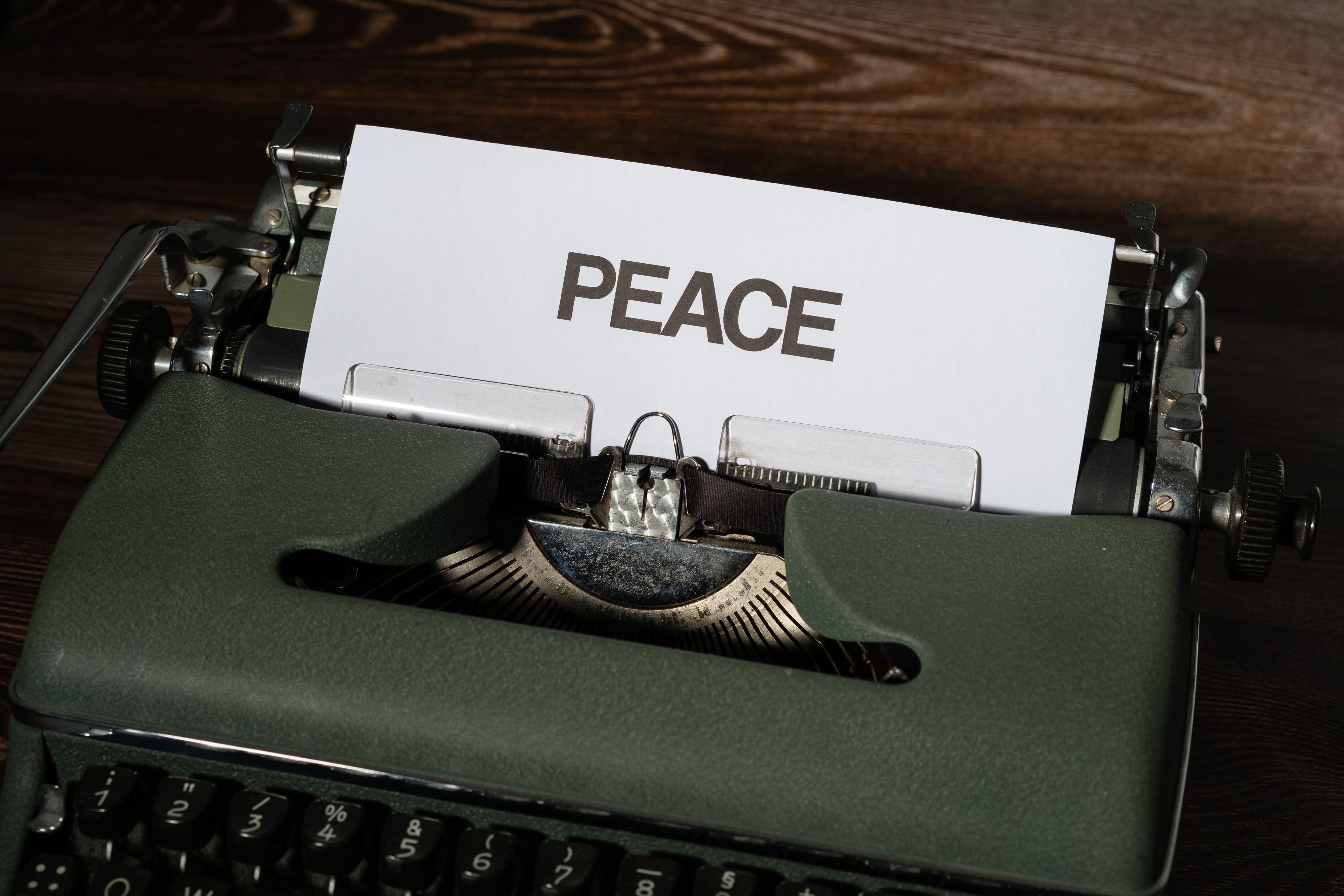 A close-up shot of a vintage typewriter with the word PEACE printed on white paper.