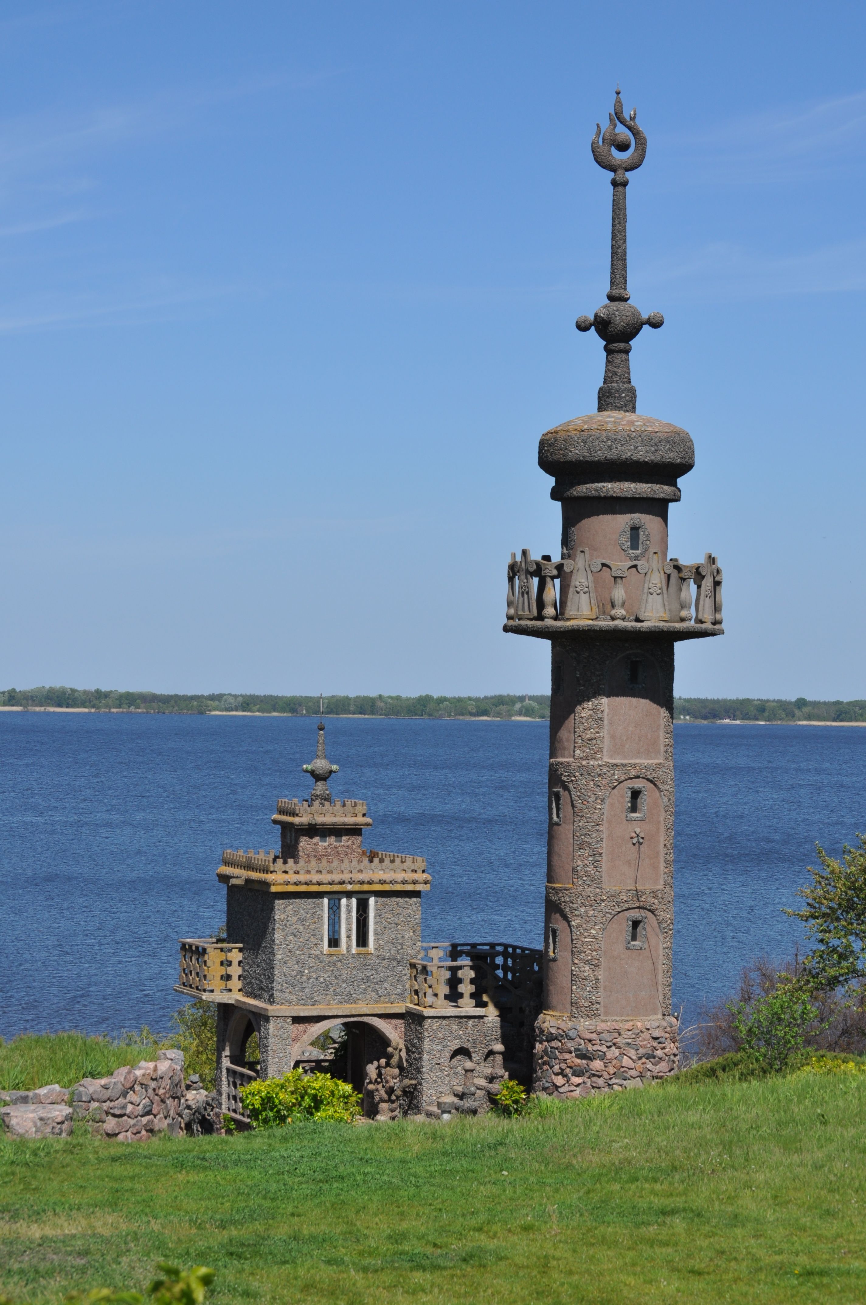 Stone tower and cottage by a river, ideal for exploring architectural uniqueness and tranquility in Ukraine.
