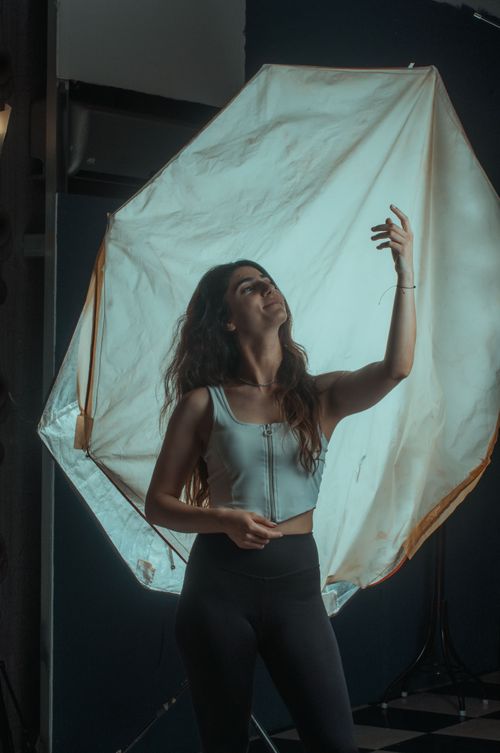 Free Portrait of a woman in a photography studio adjusting her hair under professional lighting. Stock Photo