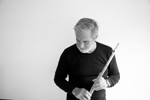 Grayscale Photo of a Man Holding a Flute
