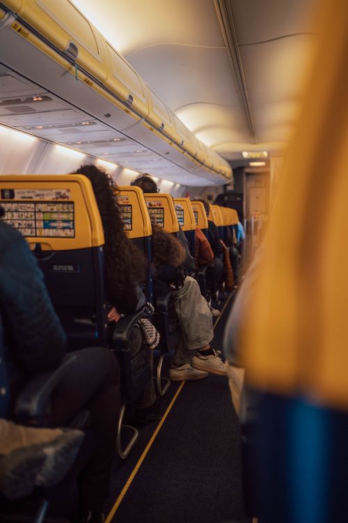 Free Interior view of an airplane with passengers seated in economy class, showcasing travel atmosphere. Stock Photo