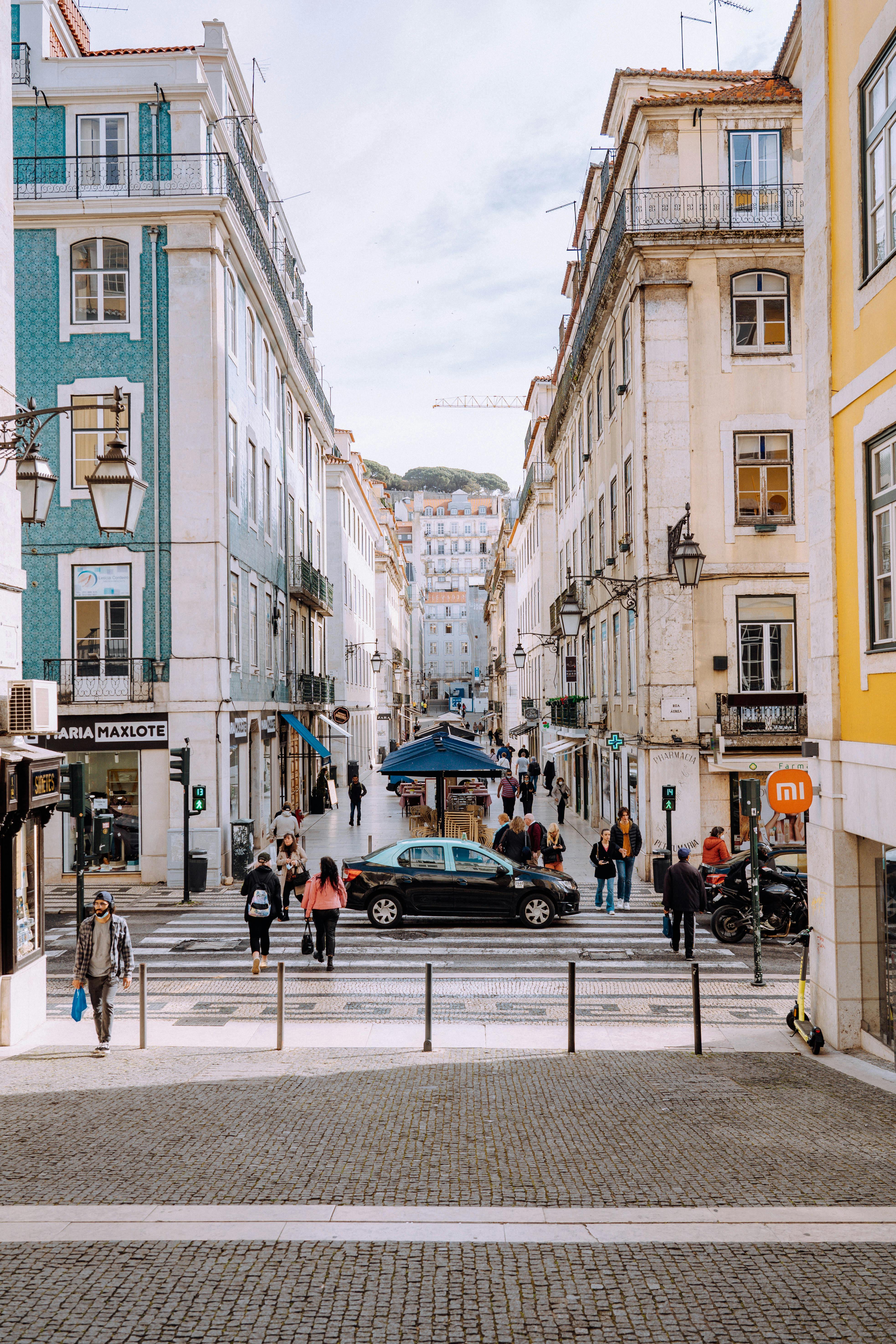 A vibrant urban scene captures a busy street with pedestrians in Lisbon's historic Bairro Alto neighborhood.