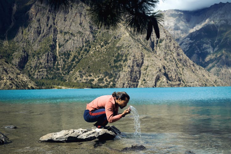 Man Sitting On A Rock Splashing Water On His Face