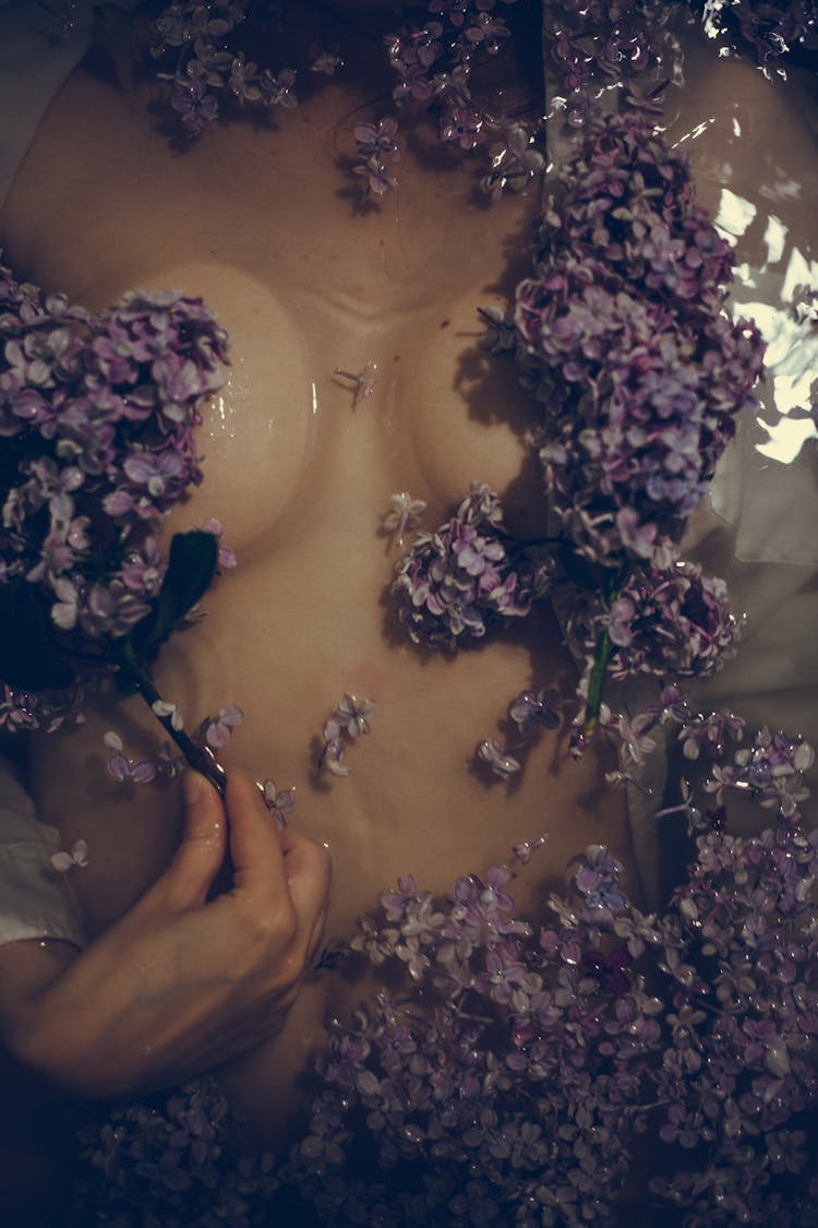 A Person Soaking On The Water With Purple Flowers Floating