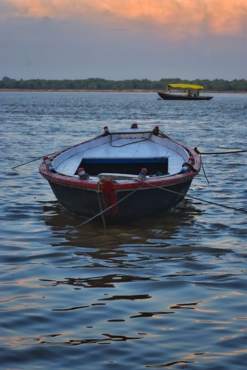Free Tranquil scene of a boat on the Ganges River in Varanasi at sunset, showcasing calm waters. Stock Photo