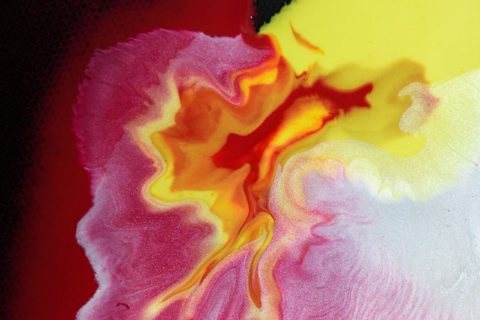 Dynamic and vibrant abstract painting with swirling red, yellow, and white colors.