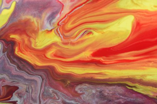 Free Dynamic close-up of swirling acrylic paints in vibrant hues of red, yellow, and purple. Stock Photo