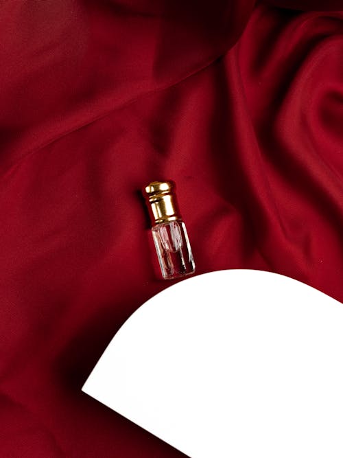 Free Perfume Bottle on a Red Silky Fabric Beside while Platform Stock Photo