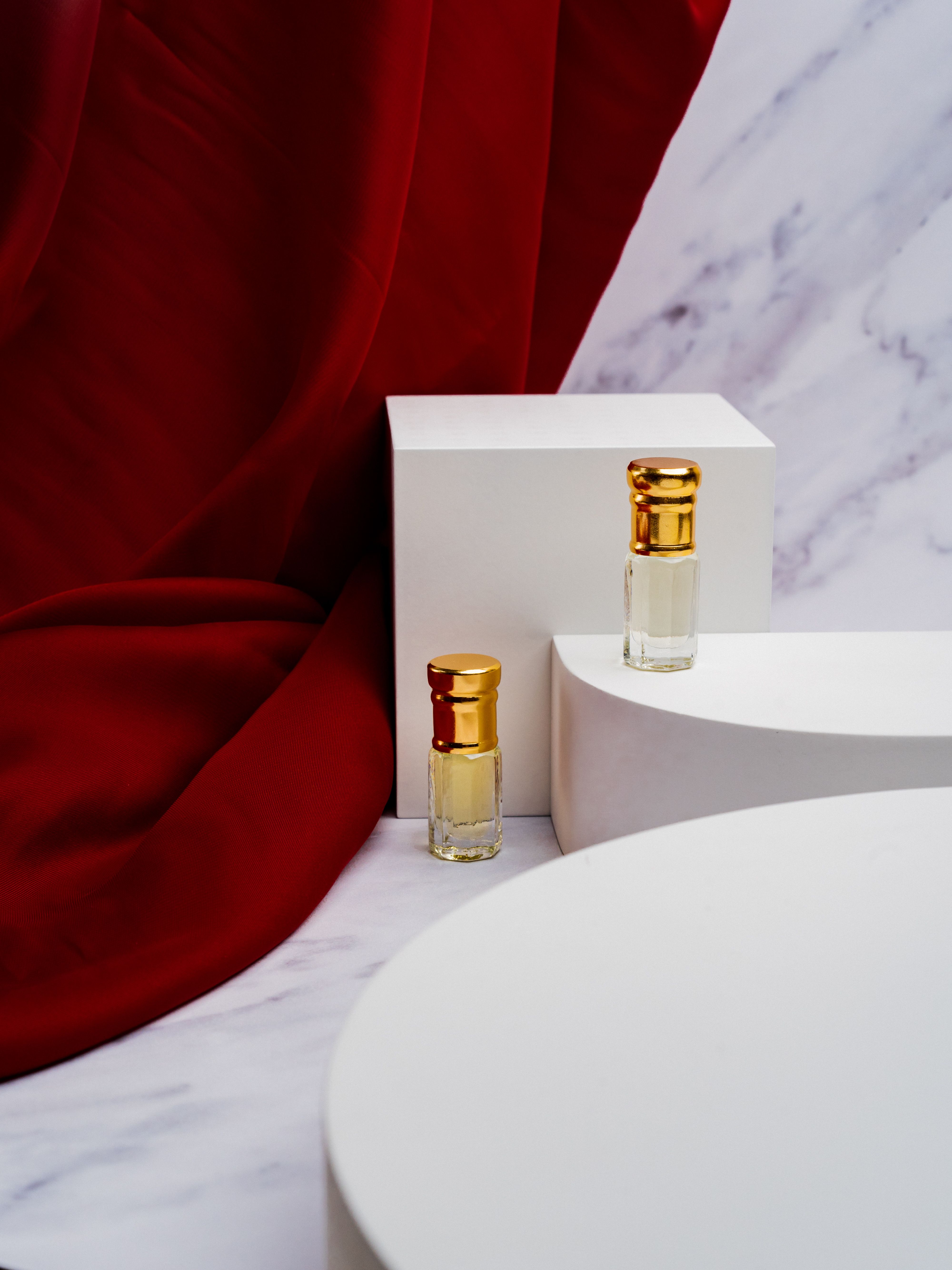 Sophisticated perfume bottles displayed on a marble surface with a striking red backdrop, exuding elegance.