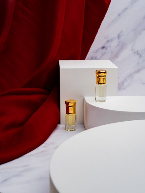 Perfume Bottles on White Platform Near Hanging Red Fabric