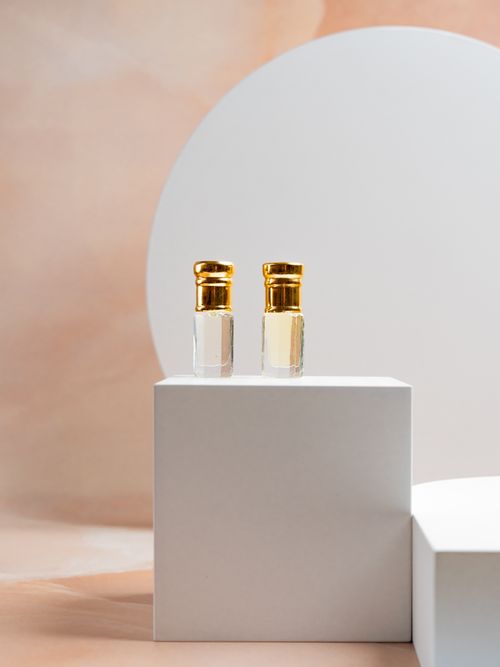 Free Minimalist product photography of perfume bottles with gold caps on white geometric platforms. Stock Photo
