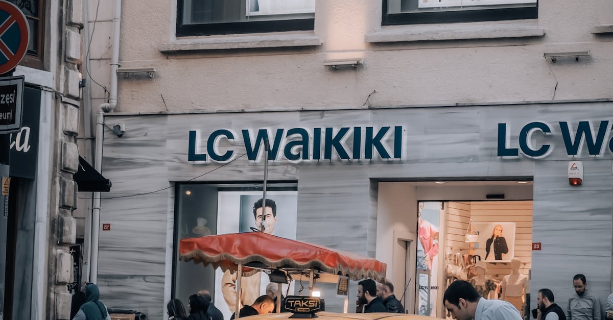 Photo by Fatih Sucu Yellow taxi in front of LC Waikiki store with people walking on a busy street.