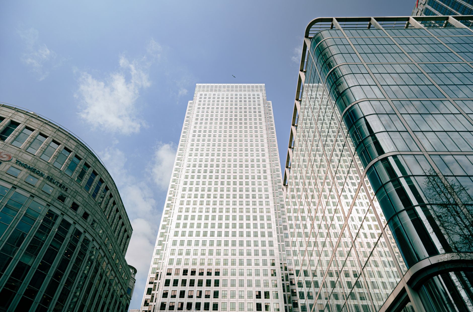 Low-angle view of iconic skyscrapers in London's bustling business hub with blue sky background.