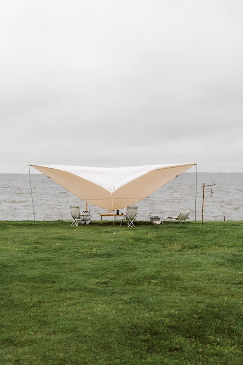 Free Tent and chairs set up by the sea under overcast sky. Ideal for outdoor events. Stock Photo