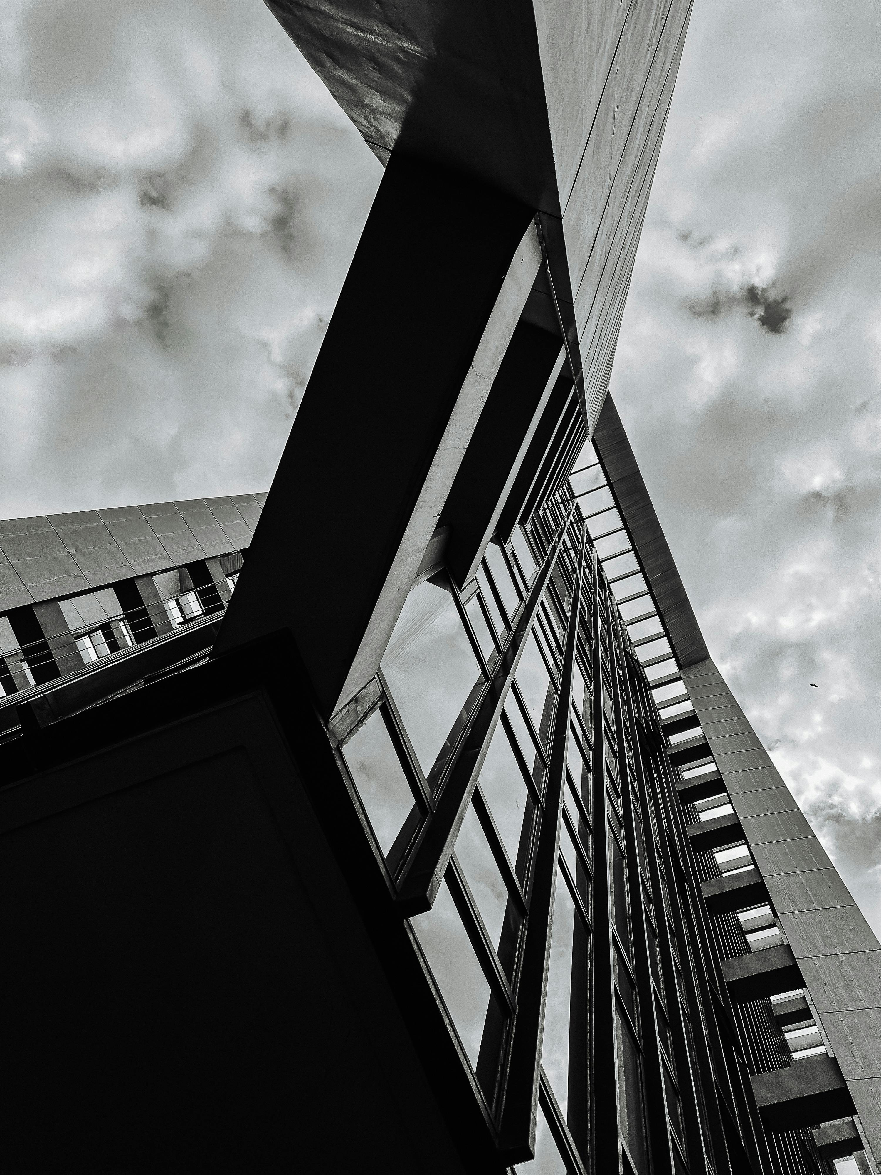 Black and white low angle photo of urban building with dramatic sky.