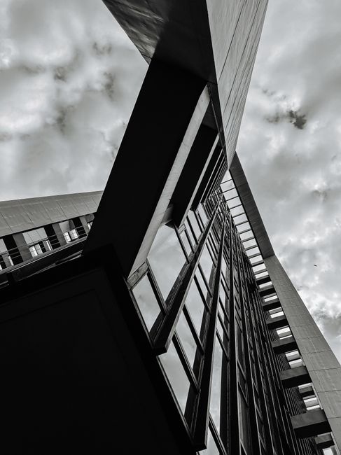 Black and white low angle photo of urban building with dramatic sky.