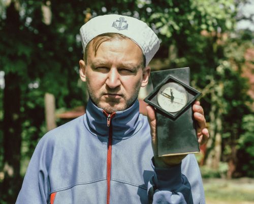 Free Portrait of a man in a sailor cap with a vintage clock outdoors. Stock Photo