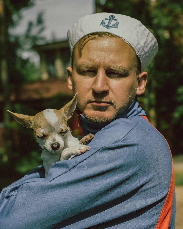 Man Wearing Sailor Cap Holding A Dog