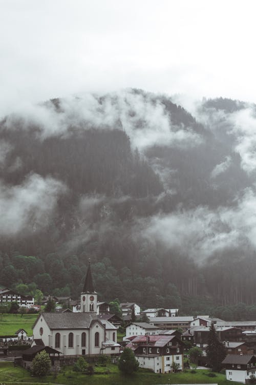 Drone Shot of Houses near Foggy Mountains