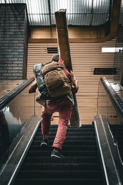Free Back view of a backpacker carrying a load on an escalator in a New York City setting. Stock Photo