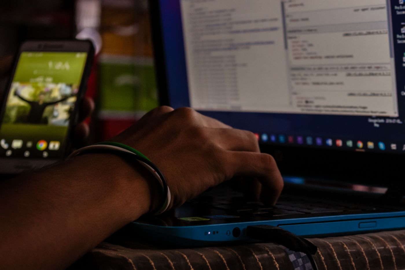A laptop and a smartphone on a desk in low light