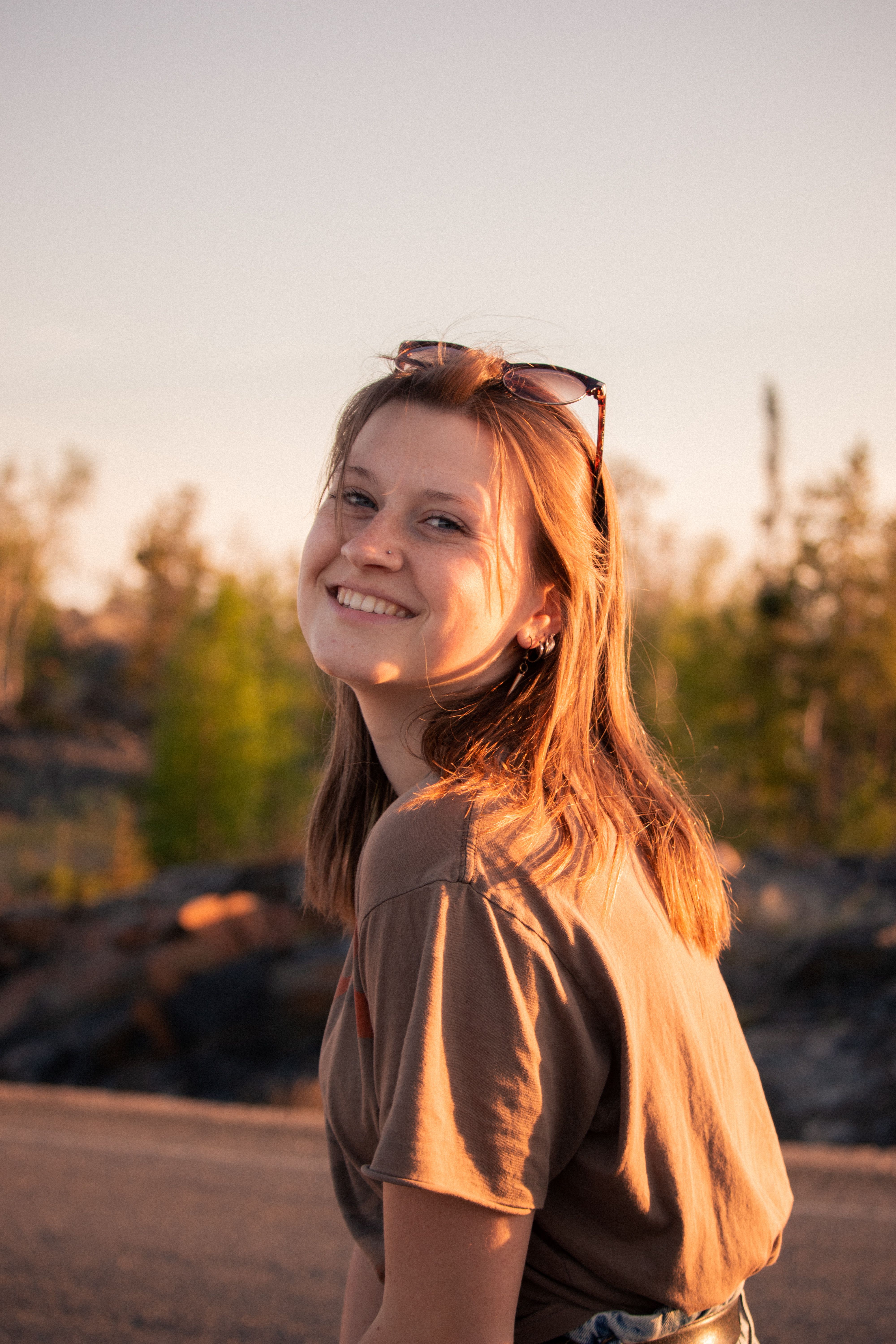 Portrait of a smiling woman outdoors with soft golden light during sunset. Casual and natural setting.