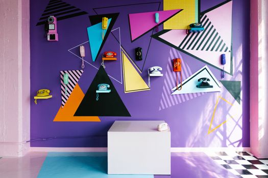 Vibrant display of vintage telephones on a geometric-patterned wall in an indoor setting.