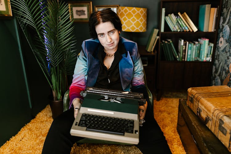 Woman Sitting And Holding A Retro Writing Machine 