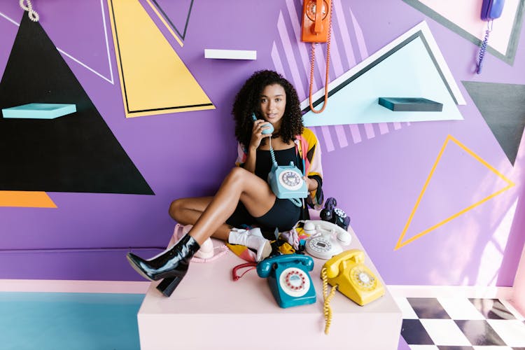 Woman Sitting With Telephones Around