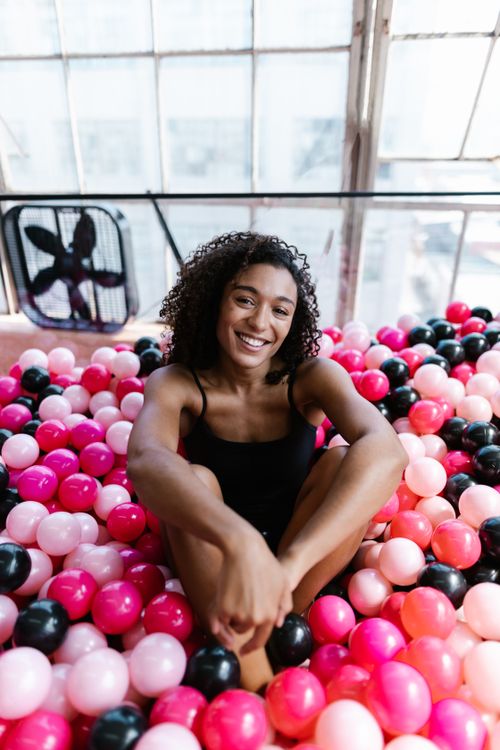 Free A happy woman enjoying colorful plastic balls indoors, capturing a joyful moment. Stock Photo