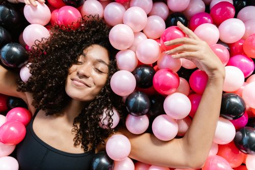 Free Smiling woman lying in a vibrant mix of colorful balls, creating a joyful and playful mood. Stock Photo