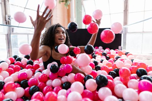 Free A joyful woman plays with colorful balls in a bright and fun indoor setting. Stock Photo