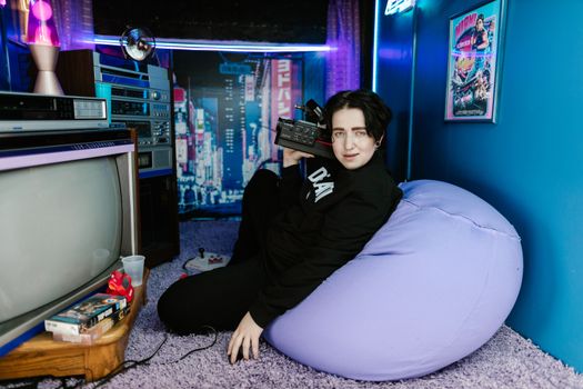 A young person relaxing with vintage tech in a retro-themed room full of nostalgic details.